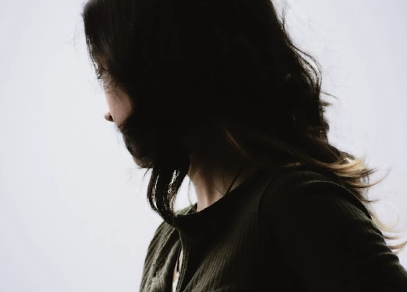 A woman with long black hair looks away from the camera, protecting her privacy.