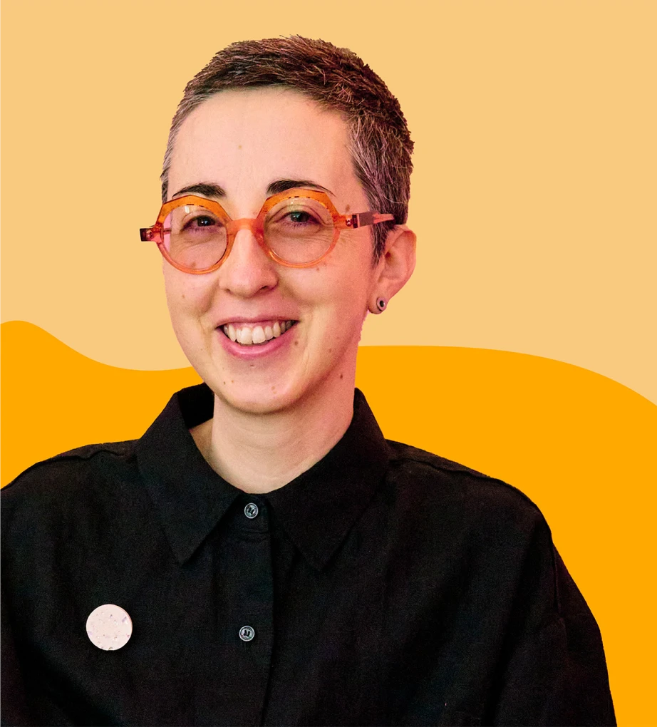 Hannah smiling, wearing orange glasses, with short brown hair, and colourful orange shapes background.