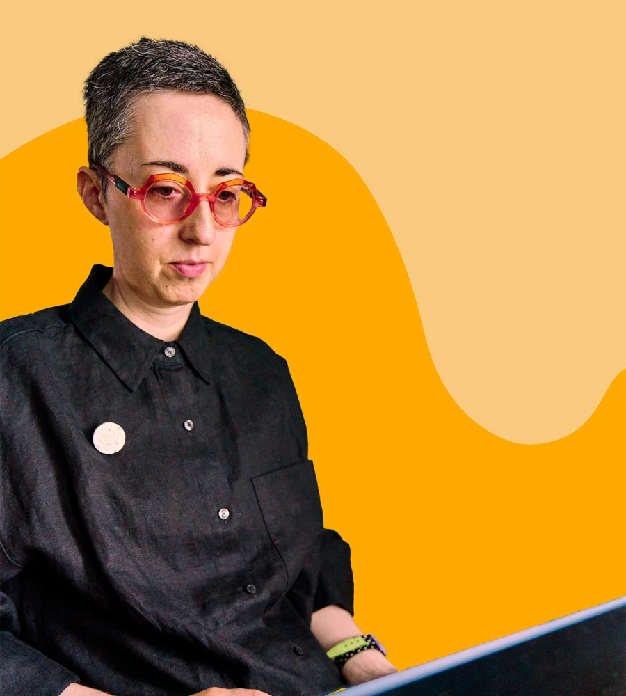 Hannah working on her laptop in her office, concentrating, with orange shapes in background.